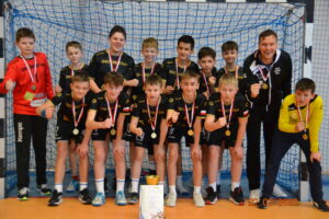 Zawodnicy piłki ręcznej stojący z medalami po turnieju na hali sportowej