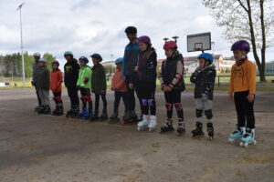 Dzieci stojące w rolkach obok stadionu w Lipuszu wraz z dorosłymi