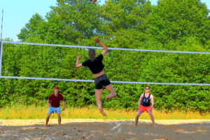 Zdjęcie zawodników grających w piłkę siatkową plażową
