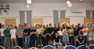 Zdjęcie przedstawia uczestników turnieju darta po skończonym turnieju, widać z tyłu 4 tarcze