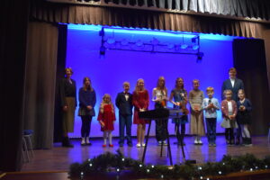 Zdjęcie przedstawia grupe dzieci i 2 kobiety stojących po koncercie na scenie