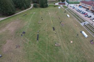 Zdjęcie toru przeszkód, na dalszym planie jest Szkoła, parking oraz orlik
