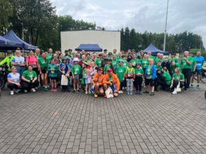 na zdjęciu widać uczestników III Radu Rowerowego Szlakiem Nawałnicy na boisku asfaltowym. Większość z nich ubrana jest w zielone koszulki i ma medale na szyi