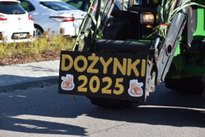 na zdjęciu widać fragment traktora , wysięgnika na którym umieszczony jest żółty napis DOŻYNKI 2025.