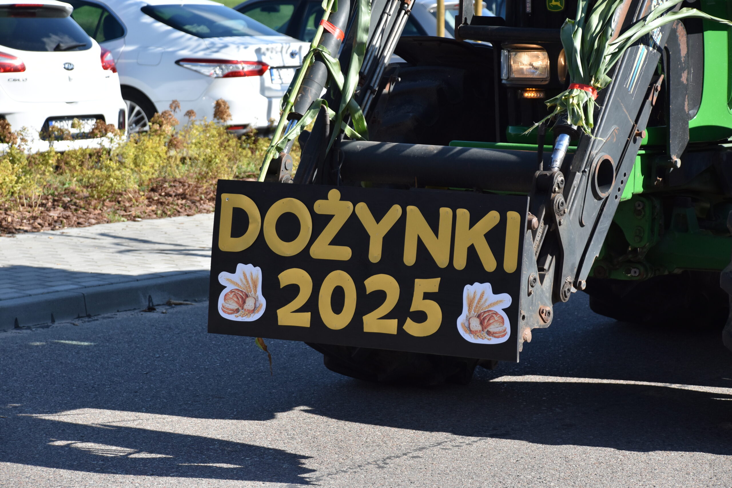 na zdjęciu widać fragment traktora , wysięgnika na którym umieszczony jest żółty napis DOŻYNKI 2025.