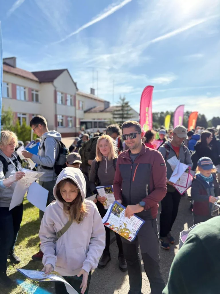 na zdjęciu widać grupę osób trzymających mapy przed startem, na pierwszym tle dziewczynka w jasnofioletowej bluzie