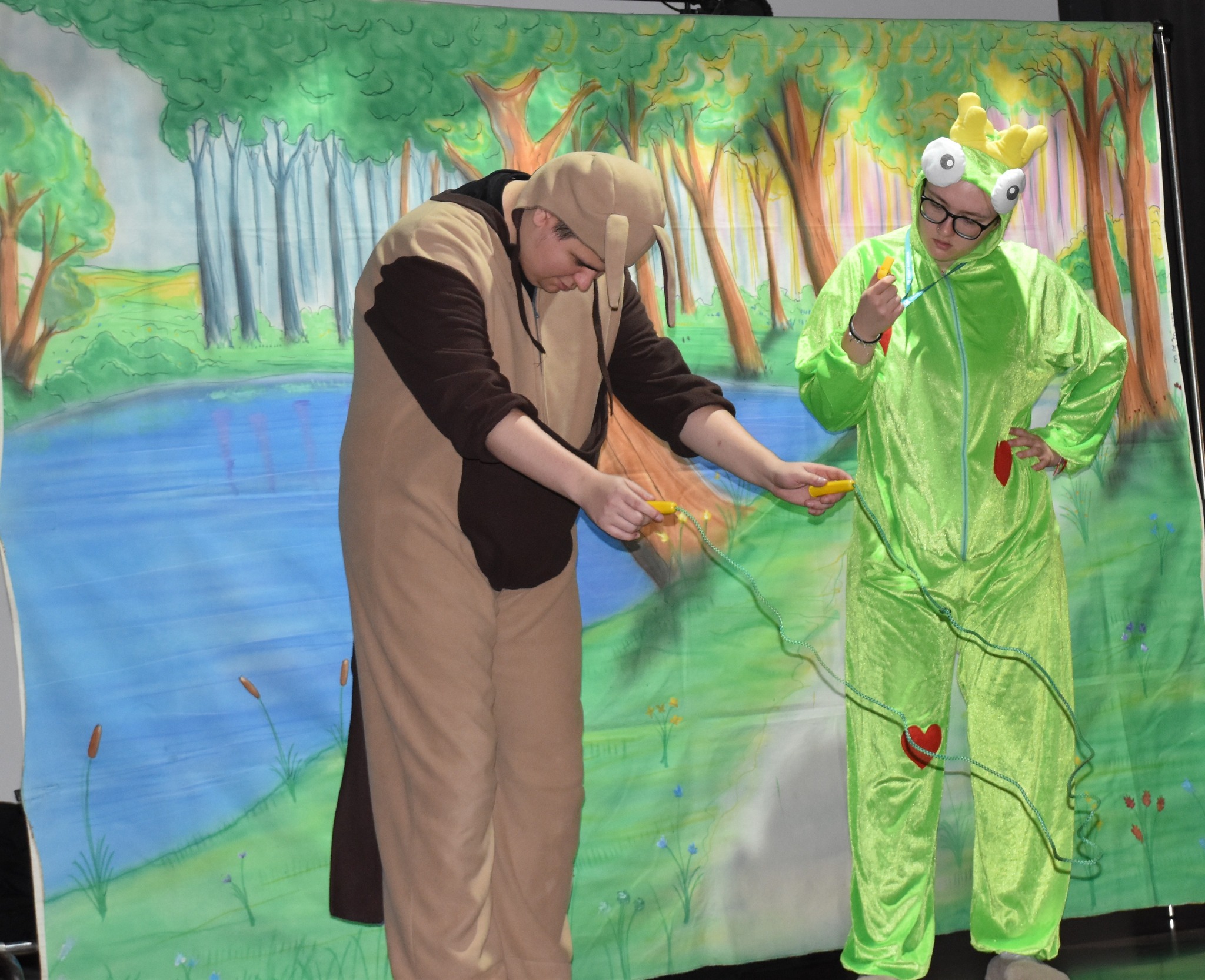 Aktorzy grający podczas przedstawienia w GOKSiR Lipusz, ubrani na zielono oraz brązowo