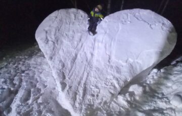 praca wyróżniona w konkursie Serce ze Śniegu. WIdać ogromne serce ulepione ze śniegu, a na nim siedzi chłopiec, który jest 4 razy mniejszy od ulepionego serca
